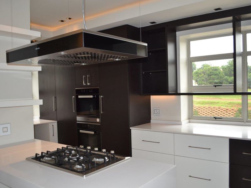 Modern kitchen featuring dark and white cabinetry, quartz countertops, a central island with a gas hob, and high-end built-in appliances.