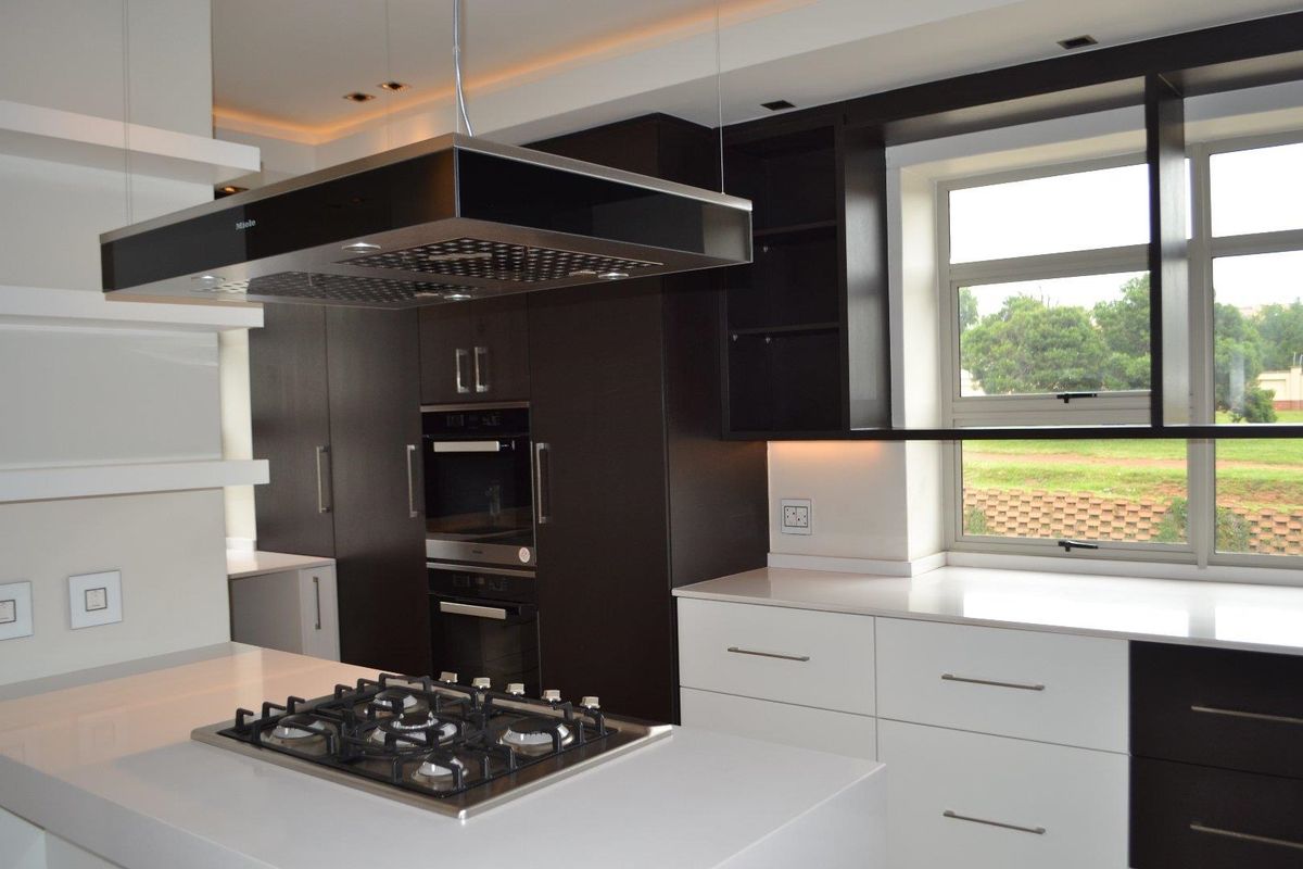 Modern kitchen featuring dark and white cabinetry, quartz countertops, a central island with a gas hob, and high-end built-in appliances.
