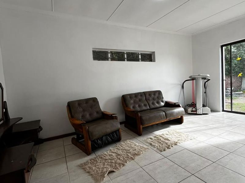 A bright living area featuring neutral tiled flooring, a horizontal clerestory window, and a sliding glass door providing access to the exterior.