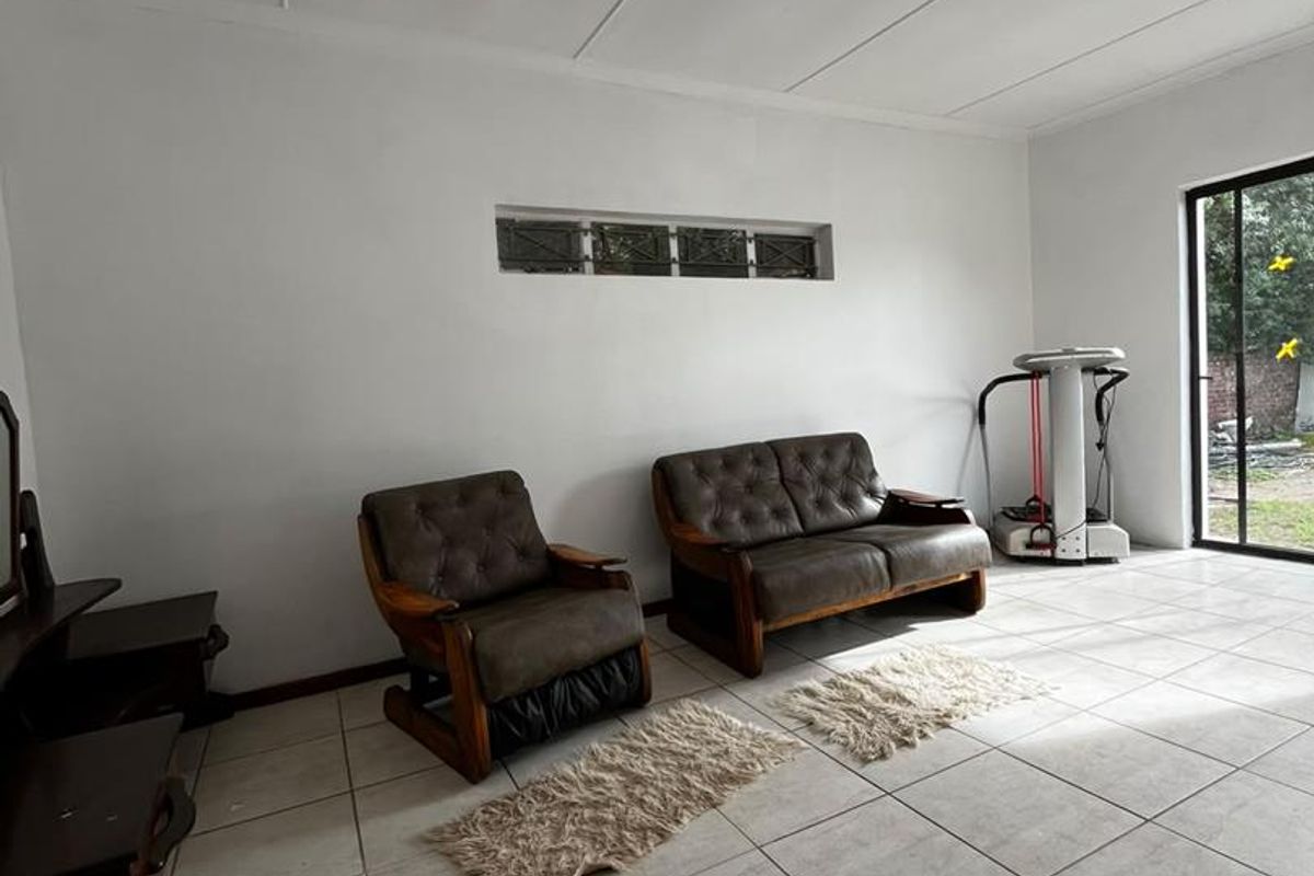 A bright living area featuring neutral tiled flooring, a horizontal clerestory window, and a sliding glass door providing access to the exterior.
