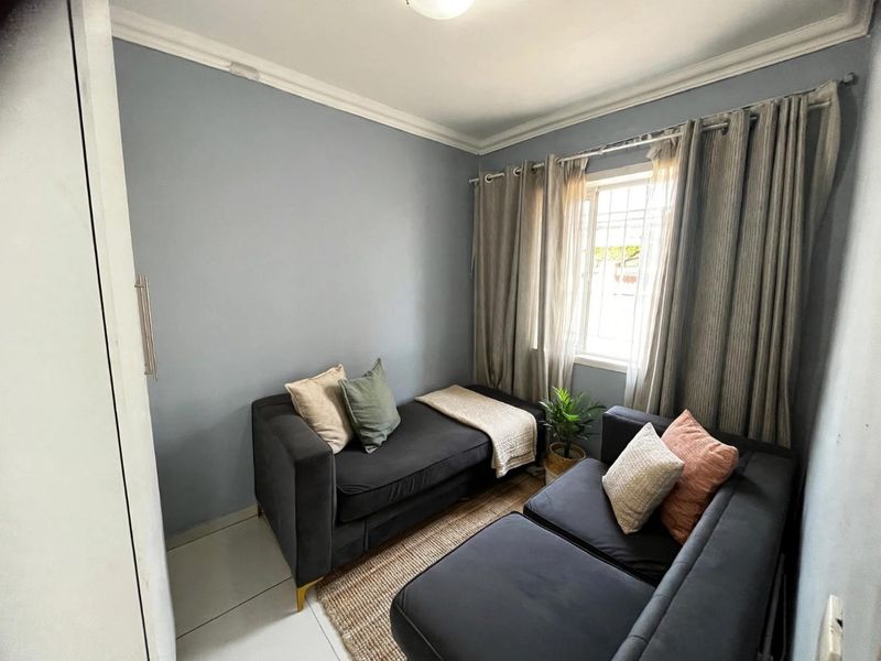 A compact bedroom featuring tiled flooring, a built-in cupboard, and decorative cornice detailing, providing a functional and well-maintained living space.