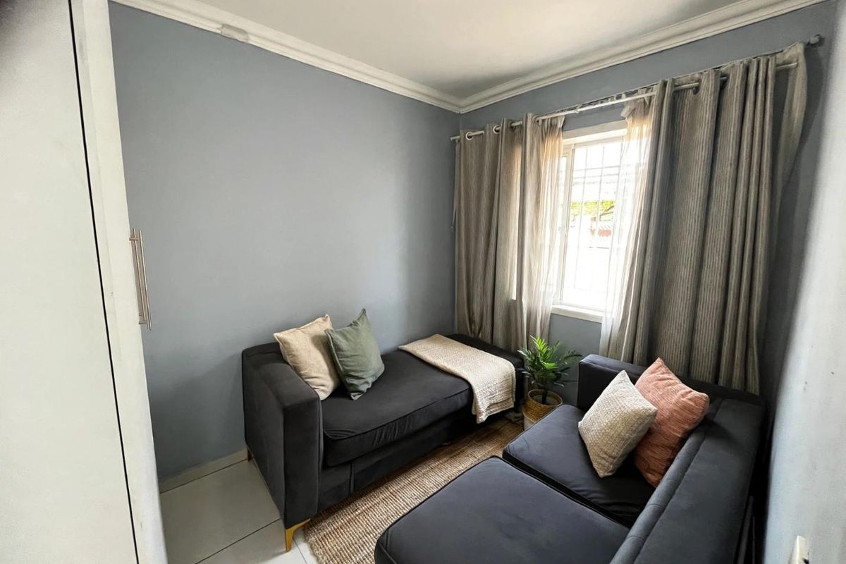 A compact bedroom featuring tiled flooring, a built-in cupboard, and decorative cornice detailing, providing a functional and well-maintained living space.