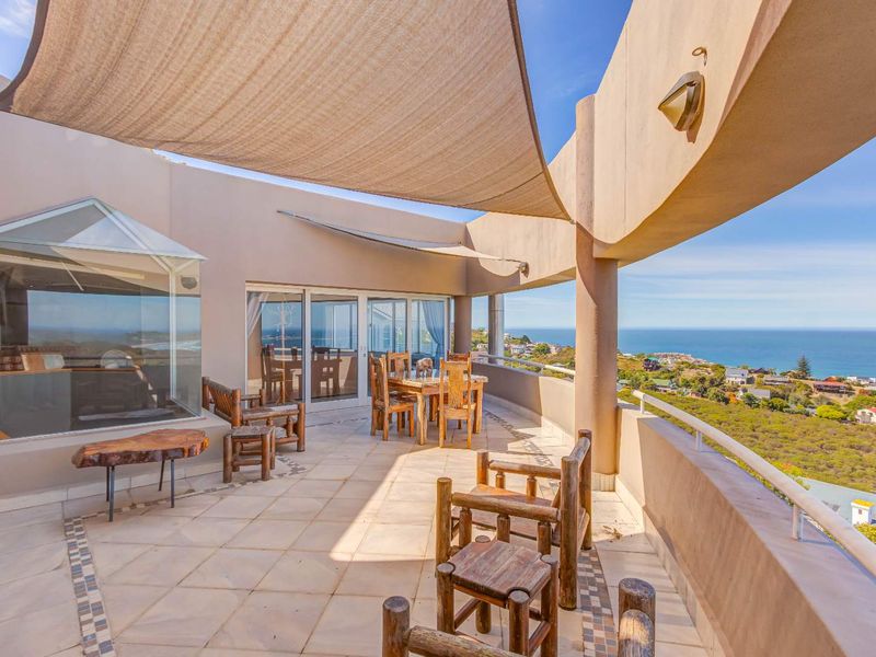 Spacious covered balcony featuring tiled flooring, a shade sail, and panoramic coastal views, providing an ideal outdoor entertainment area.