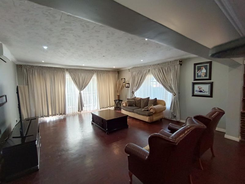Spacious living room featuring dark hardwood flooring, recessed downlighting, and large sliding glass doors that provide ample natural light.