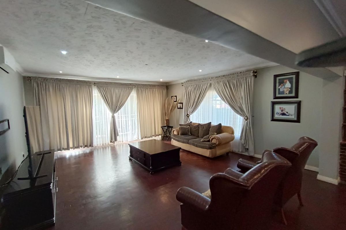 Spacious living room featuring dark hardwood flooring, recessed downlighting, and large sliding glass doors that provide ample natural light.