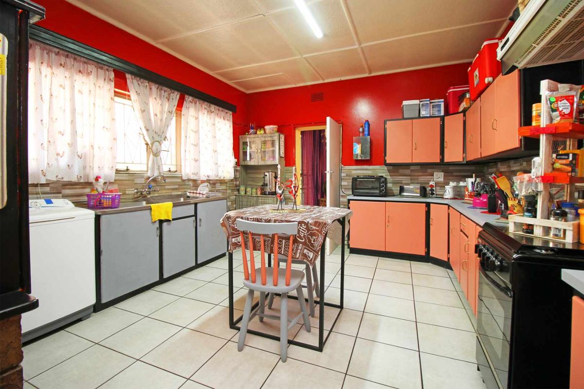 A functional kitchen featuring tiled flooring, built-in cabinetry, a double sink, and a freestanding stove, offering a practical layout for daily meal preparation.