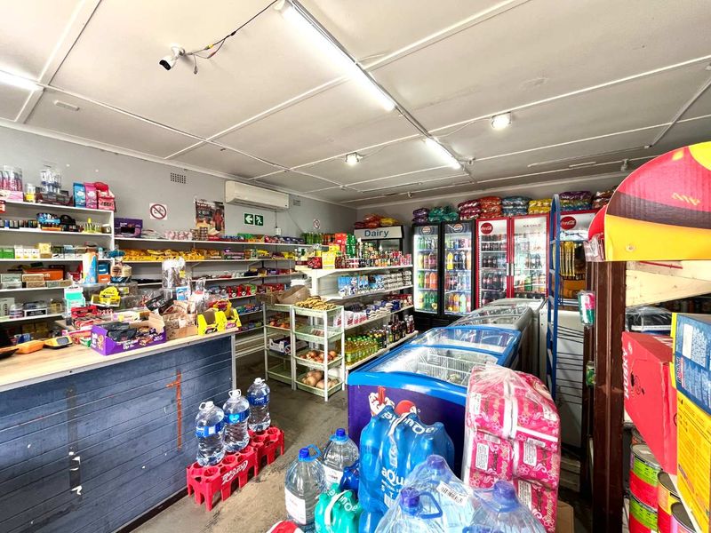 A functional retail convenience store interior featuring built-in shelving, commercial refrigeration units, and a service counter.