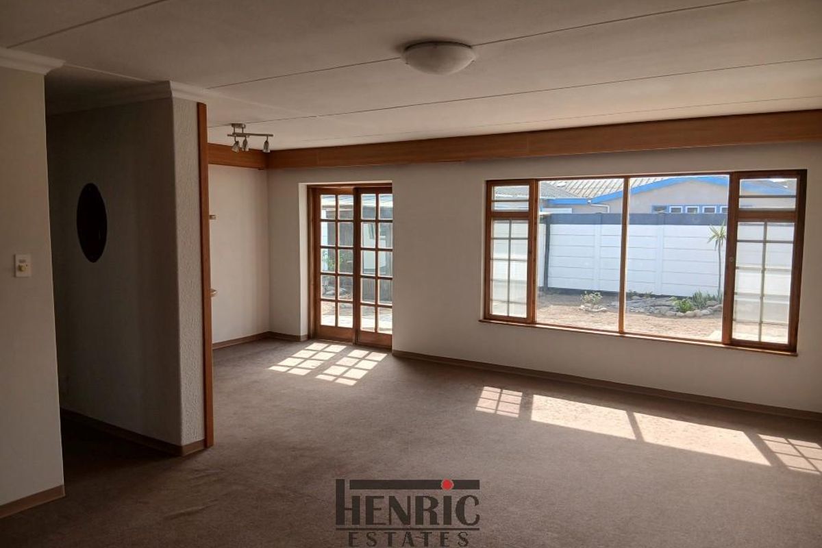 A spacious, empty living room featuring large windows and sliding glass doors that provide ample natural light and access to the exterior.