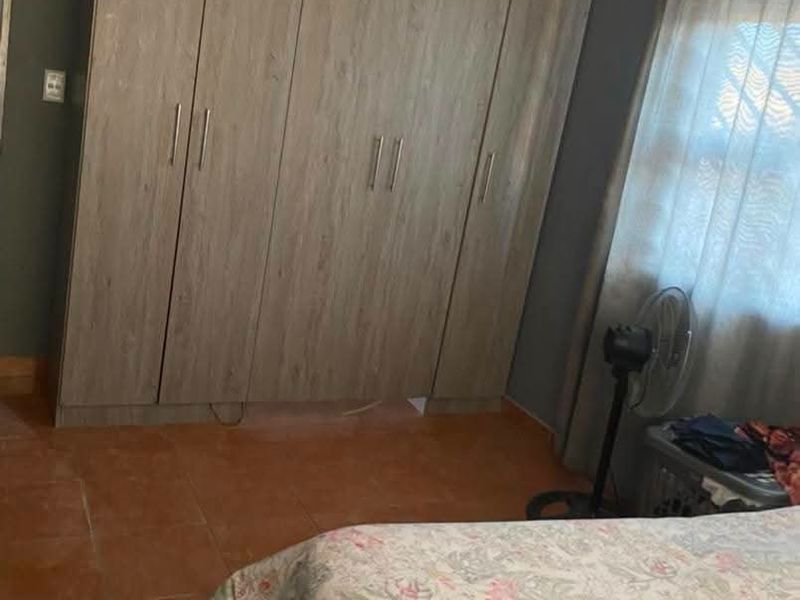 A bedroom featuring built-in wooden cupboards and tiled flooring, offering functional storage space.