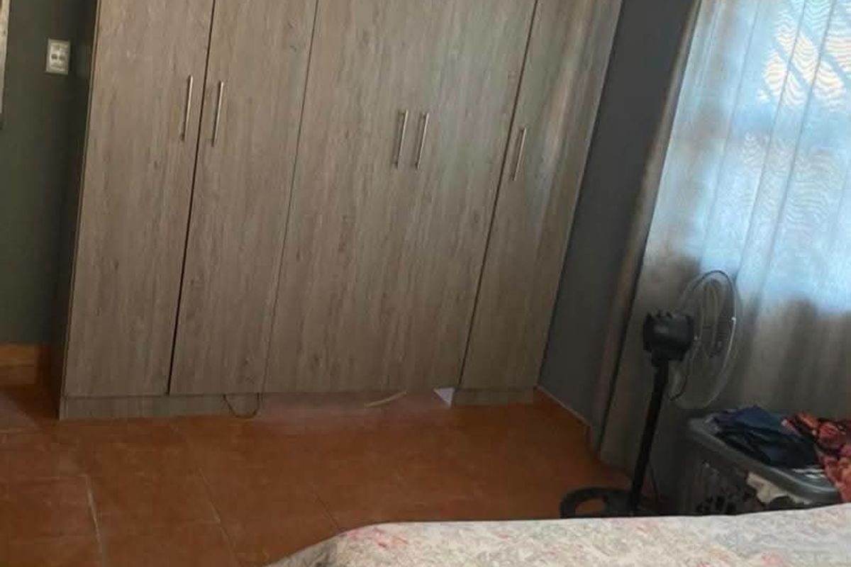 A bedroom featuring built-in wooden cupboards and tiled flooring, offering functional storage space.