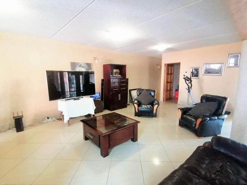 A spacious living room featuring neutral wall tones and large format floor tiles, providing a versatile area for relaxation and entertainment.
