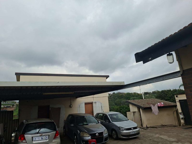 Rear exterior area featuring a functional carport structure and concrete paved driveway space.