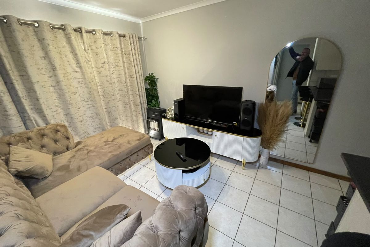 A comfortable living room featuring tiled flooring, cove cornicing, and a built-in gas heater, providing a functional and cozy space.