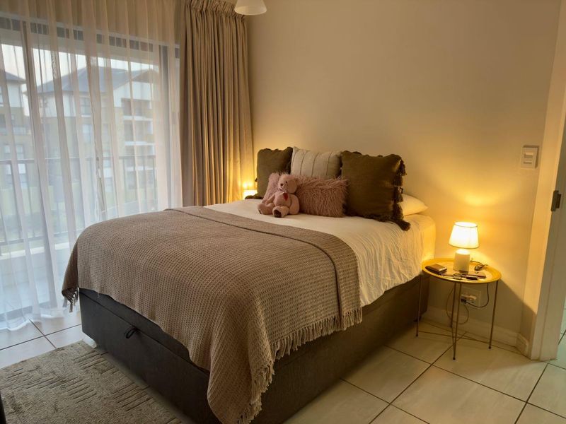A well-maintained bedroom featuring tiled flooring and a large sliding glass door that provides access to an outdoor balcony area.