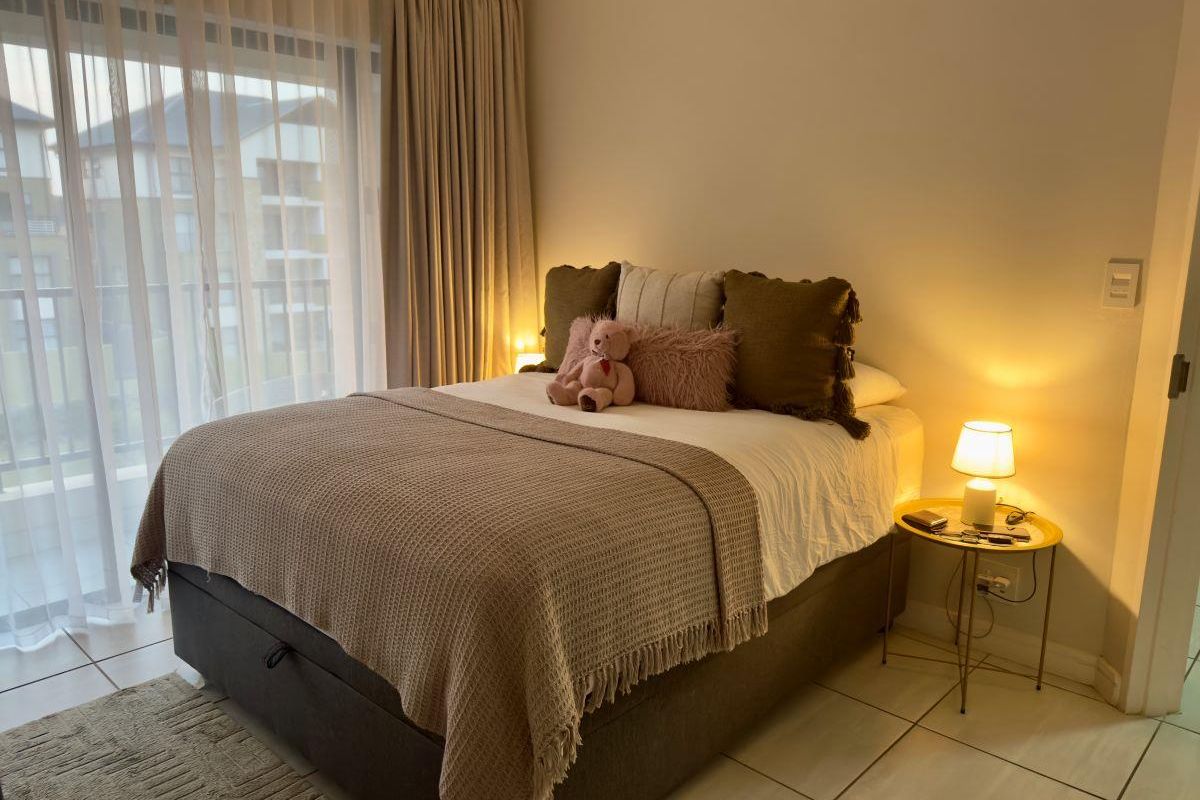 A well-maintained bedroom featuring tiled flooring and a large sliding glass door that provides access to an outdoor balcony area.