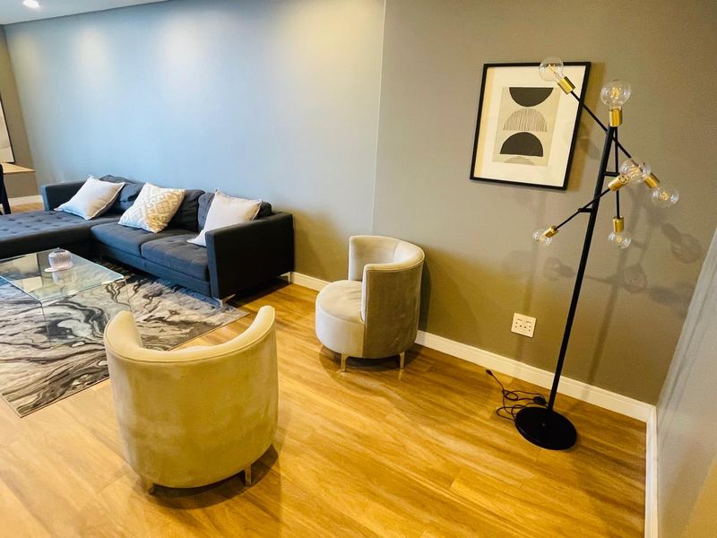 A well-maintained living room featuring modern laminate flooring, neutral wall tones, and recessed ceiling lighting, creating a comfortable and inviting atmosphere.
