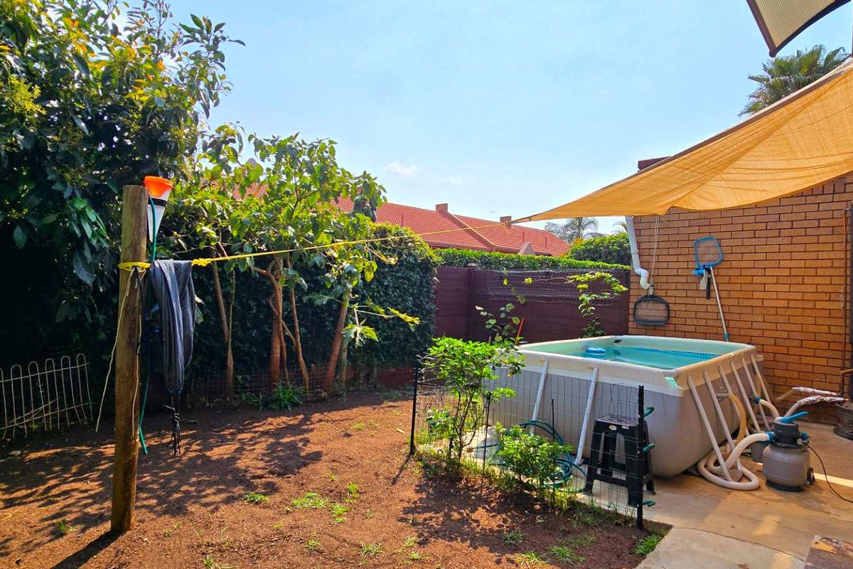 Rear garden area featuring a paved patio with a shade sail, perimeter brick walling, and an above-ground pool setup.