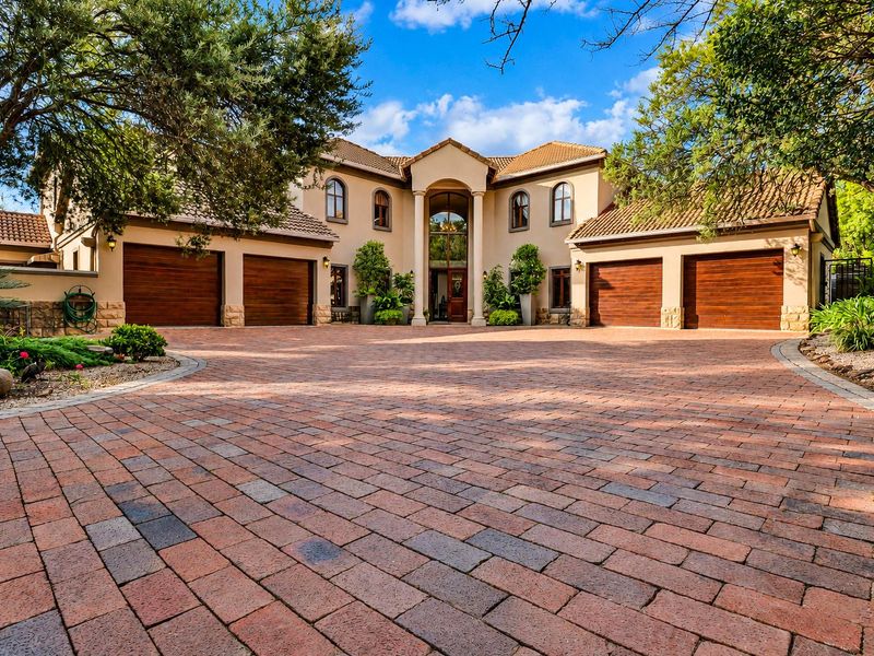 Impressive front elevation featuring a large paved driveway, four-car garage, and a grand entrance with architectural columns and arched windows.