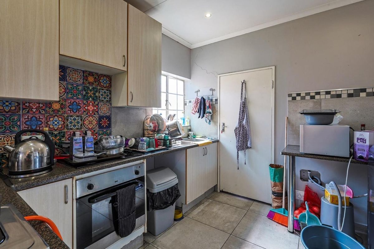 Compact kitchen featuring built-in cabinetry, integrated oven and hob, tiled flooring, and a decorative patterned splashback.