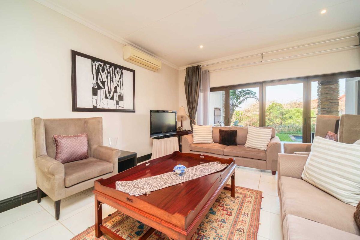 A comfortable living room featuring tiled flooring, a wall-mounted air conditioning unit, and large sliding glass doors providing access to the outdoor area.