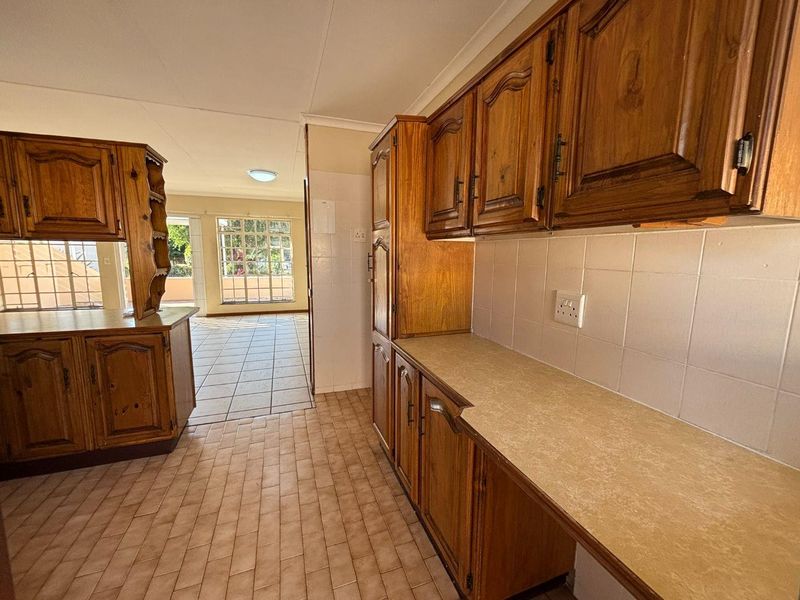 A functional kitchen featuring traditional wooden cabinetry, laminate countertops, and tiled flooring, offering a clean and well-maintained space ready for updates.