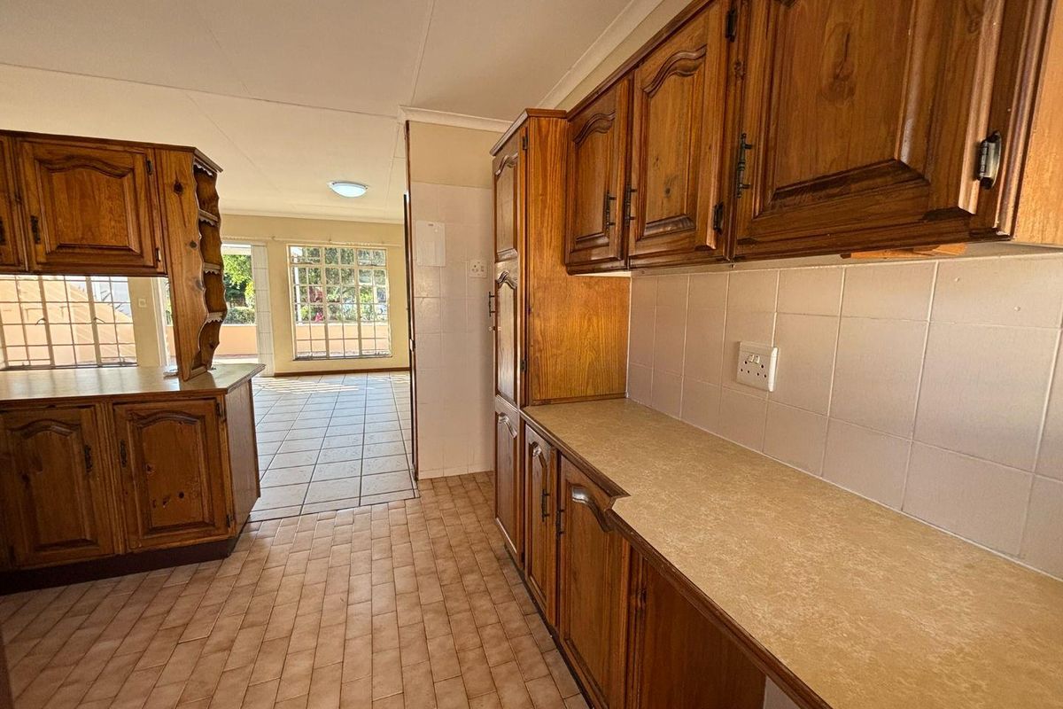 A functional kitchen featuring traditional wooden cabinetry, laminate countertops, and tiled flooring, offering a clean and well-maintained space ready for updates.