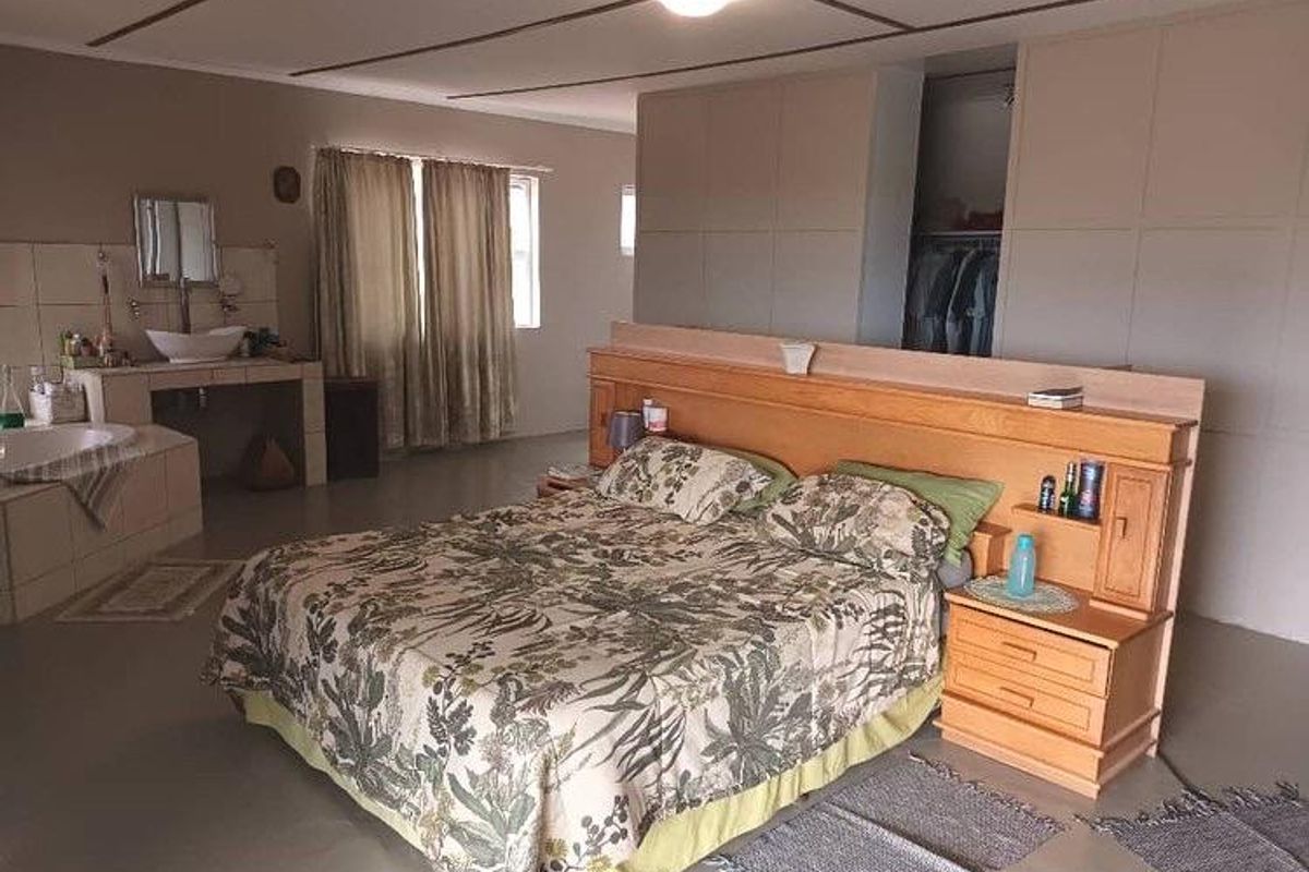 Spacious open-plan bedroom featuring an integrated en-suite bathroom area with a built-in vanity and bathtub, plus a partitioned walk-in closet space.
