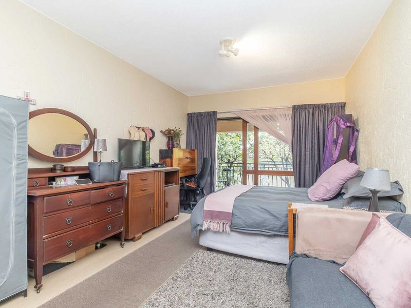 A bedroom featuring a sliding glass door that opens onto a balcony, providing natural light and outdoor access.