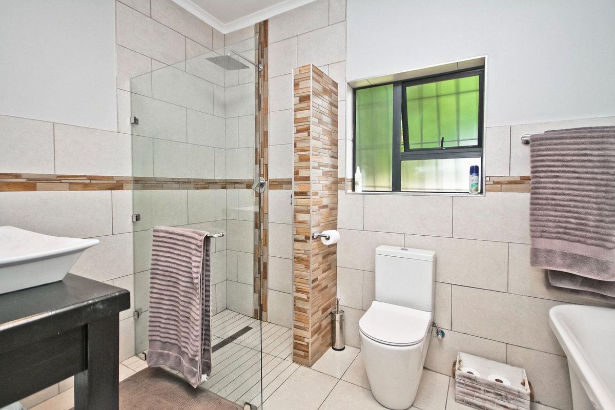 Modern bathroom featuring a glass-enclosed walk-in shower, tiled walls with decorative accents, a contemporary toilet, and a vessel sink vanity.