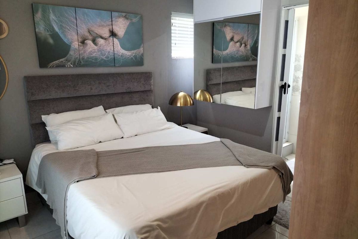 A well-maintained bedroom featuring built-in cupboards with mirrored doors, tiled flooring, and neutral wall finishes.