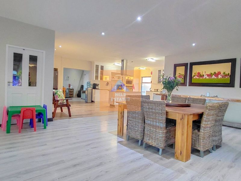 Spacious open-plan living and dining area featuring modern laminate flooring, recessed lighting, and a well-appointed kitchen with built-in cabinetry and appliances.