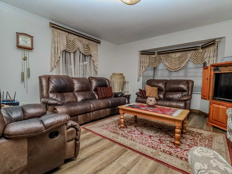 A comfortable living room featuring laminate flooring, a bay window, and coved ceiling details, providing a functional and inviting space.