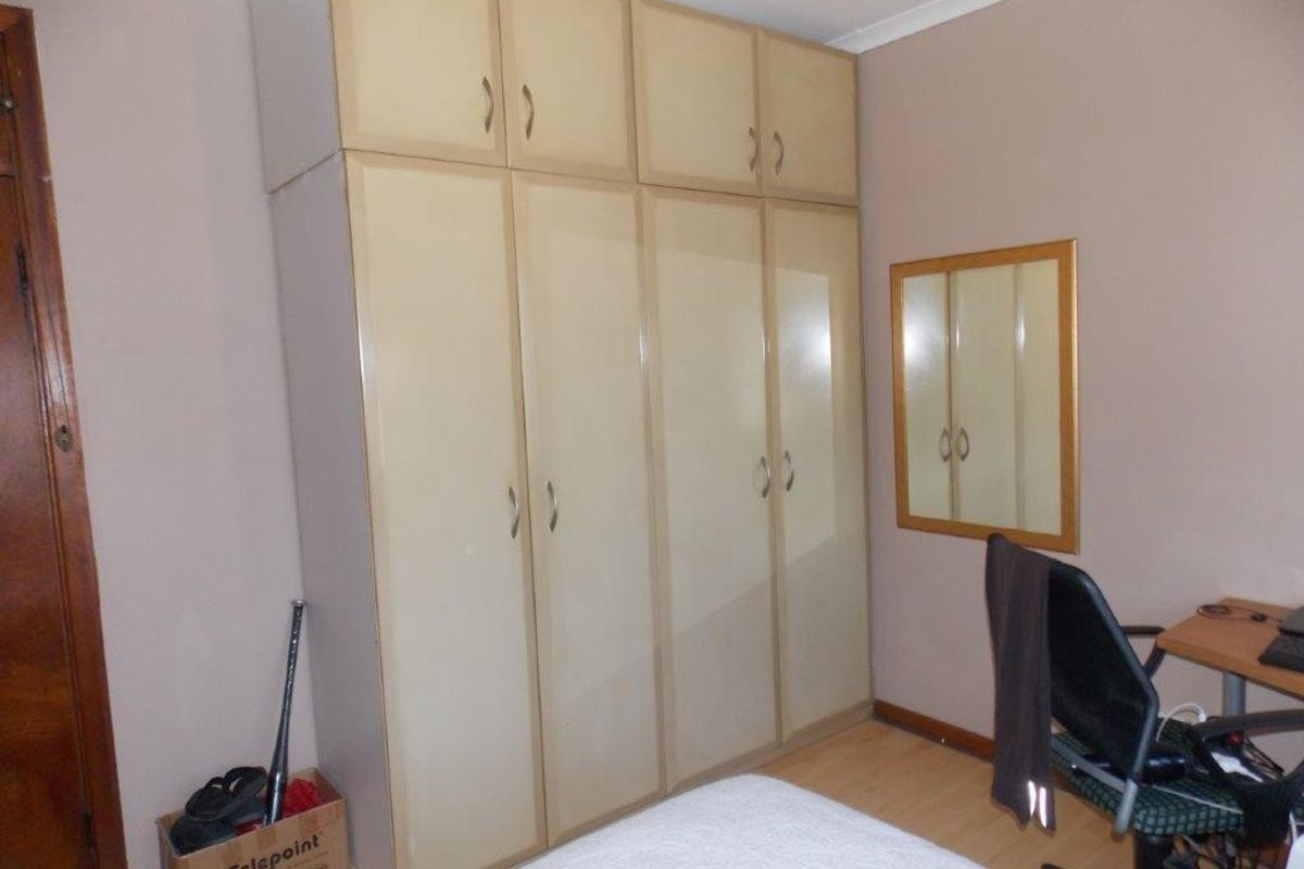 Bedroom featuring built-in cupboards with overhead storage and laminate flooring.