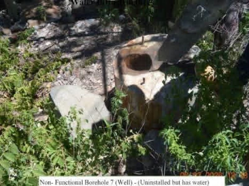 A non-functional borehole or well located on the property grounds, currently uninstalled but noted to contain water.