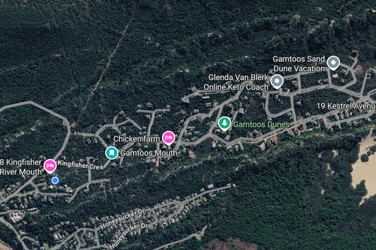 An aerial satellite view of the Gamtoos Mouth residential area, showcasing the surrounding coastal landscape, sand dunes, and local road infrastructure.