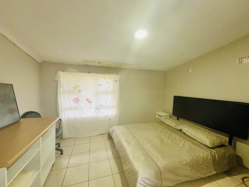 A bedroom featuring tiled flooring and recessed lighting, showing visible signs of ceiling water damage and plaster deterioration requiring maintenance.