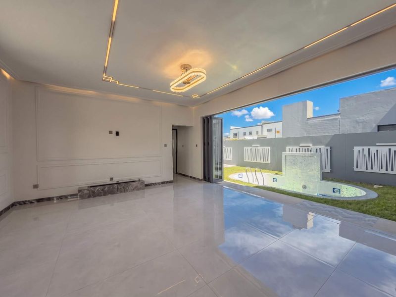 Spacious living area featuring polished marble floors, elegant wainscoting, and seamless indoor-outdoor flow through bi-fold doors to a private pool area.