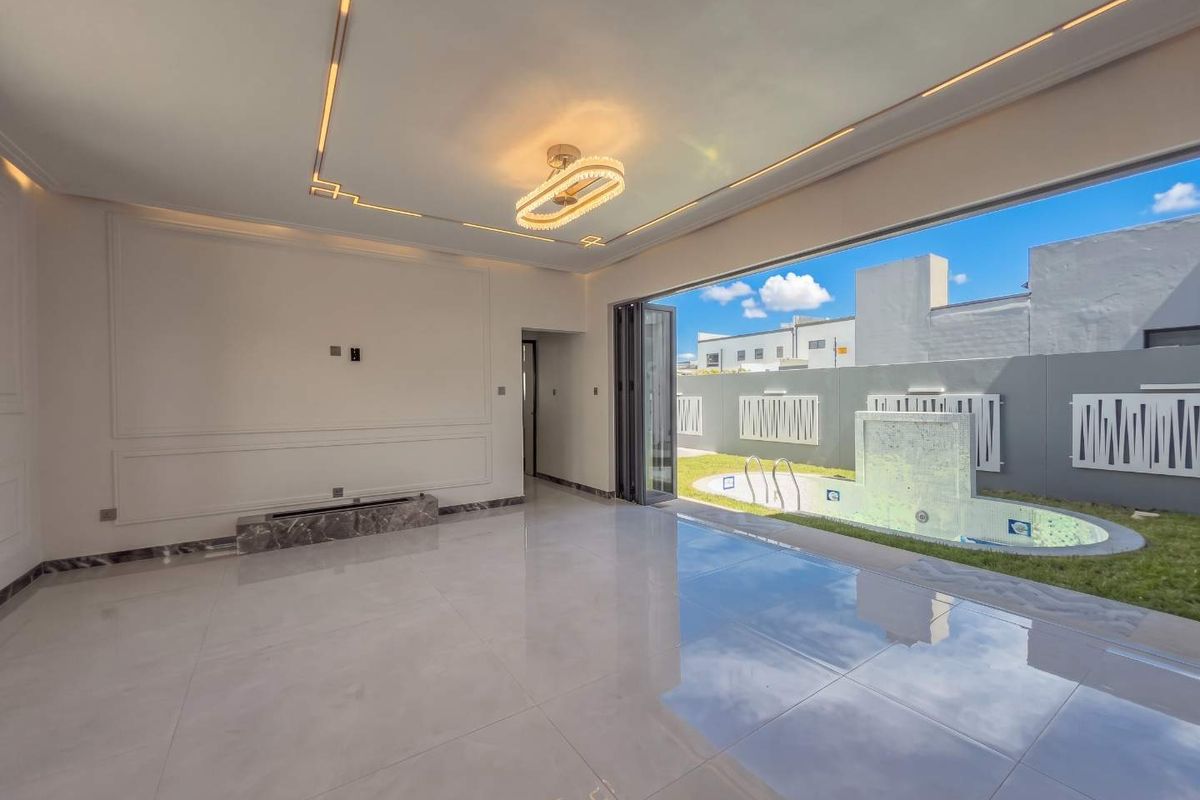 Spacious living area featuring polished marble floors, elegant wainscoting, and seamless indoor-outdoor flow through bi-fold doors to a private pool area.
