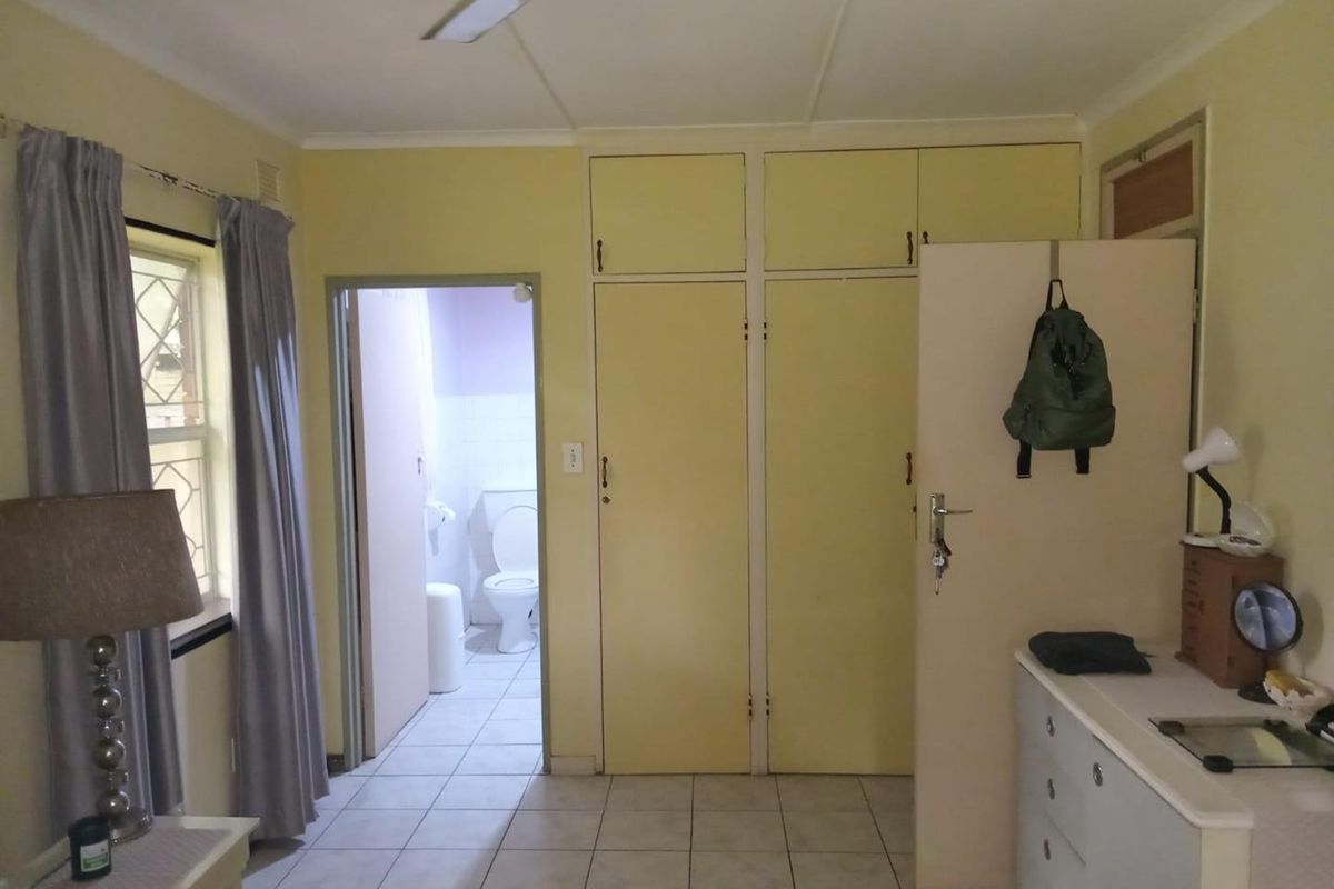 A bedroom featuring built-in cupboards and an en-suite bathroom with tiled flooring.