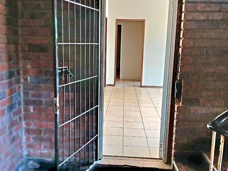 Entrance area featuring a security gate, exposed brick walls, and tiled flooring leading into the office interior.