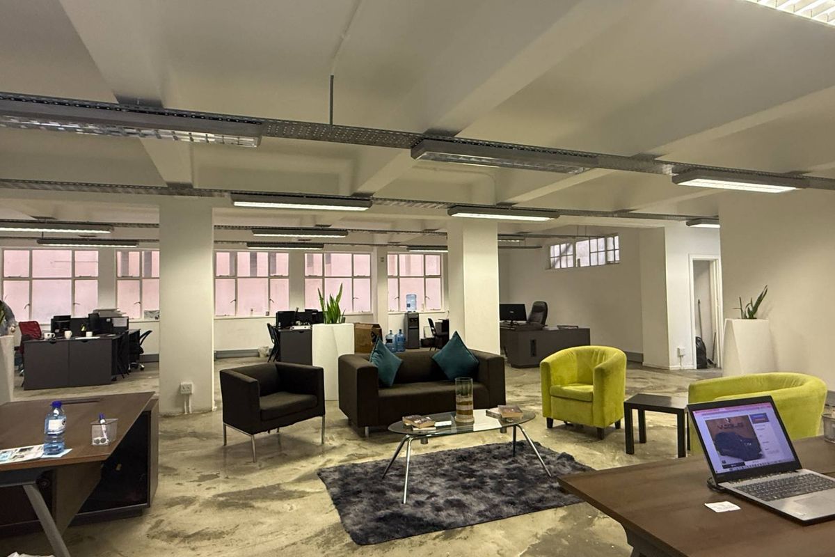 Spacious open-plan office featuring industrial-style exposed ceilings, polished concrete floors, and large windows providing ample natural light.