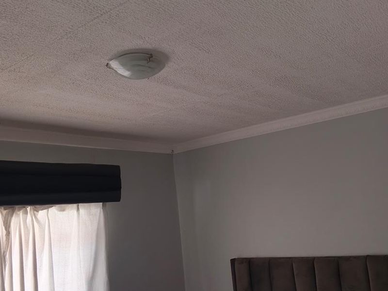 A bedroom featuring a textured ceiling with cornice detailing and a central flush mount light fixture.