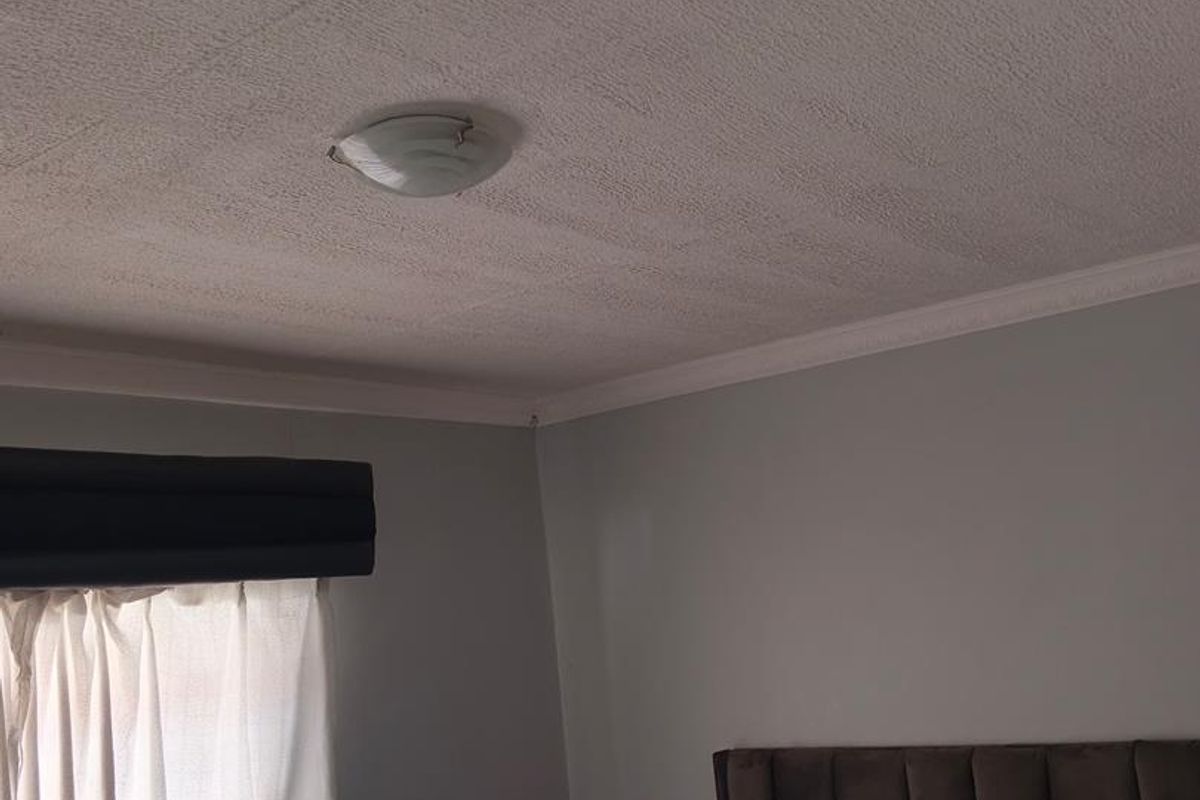 A bedroom featuring a textured ceiling with cornice detailing and a central flush mount light fixture.
