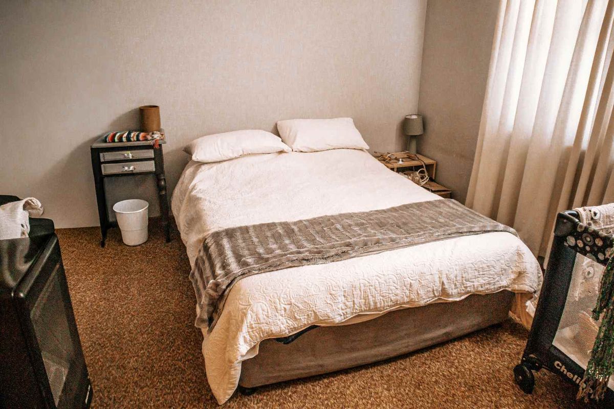 A standard bedroom featuring carpeted flooring and window curtains, providing a functional and neutral space.