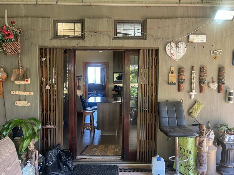 A covered patio area featuring a sliding security gate entrance leading into the home interior.