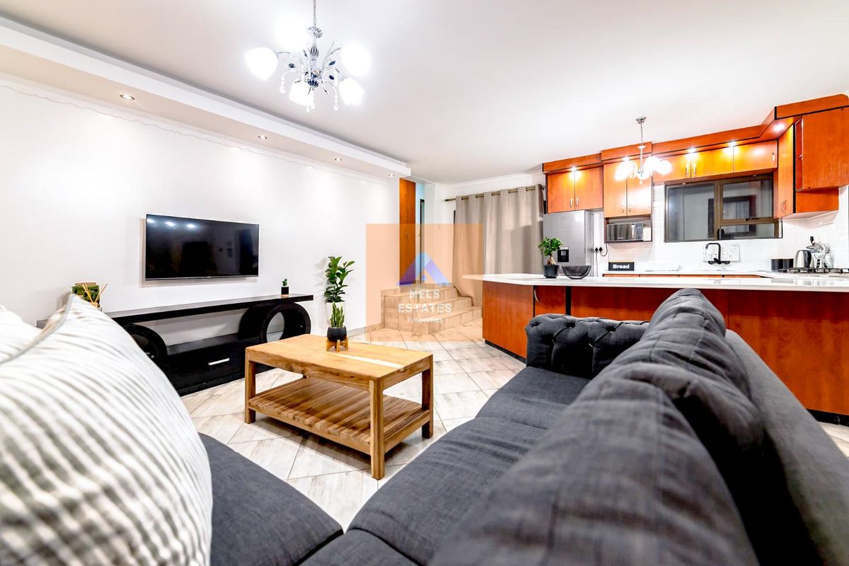 An open-plan living and kitchen area featuring tiled floors, modern cabinetry, and recessed lighting, creating a functional and cohesive living space.