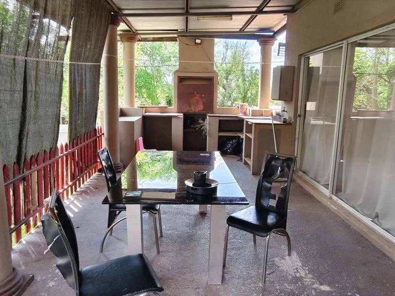 Covered patio area featuring a built-in braai, concrete columns, and sliding glass door access to the main interior living space.