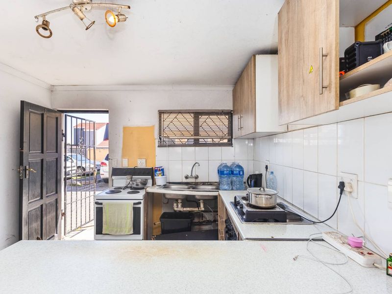 A functional kitchen featuring built-in cabinetry, a double sink, and a stove, with direct access to the exterior via a security gate.