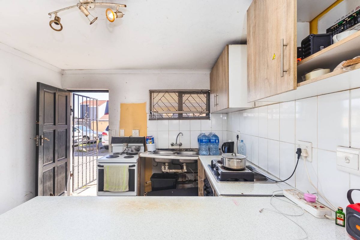 A functional kitchen featuring built-in cabinetry, a double sink, and a stove, with direct access to the exterior via a security gate.