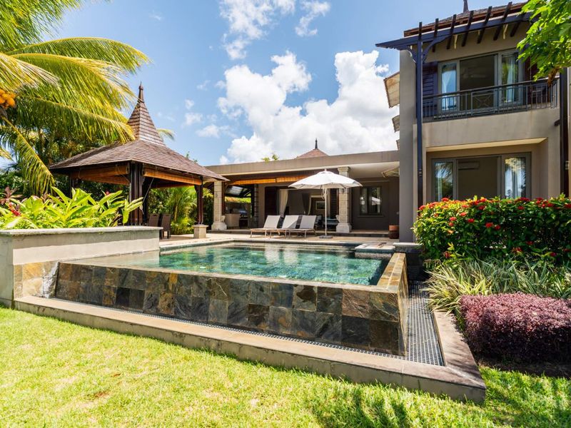 A beautifully landscaped rear garden featuring a modern swimming pool with stone tiling, a covered patio area, and a traditional gazebo.